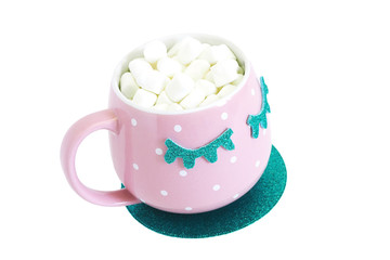A pink and white polka-dot mug with closed blue eyes with coffee and marshmallows stands on a blue shiny round stand. Isolate on a white background..