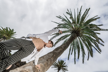 Man leaning on a palm tree