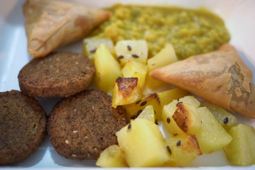 Assorted vegan plate with falafel, roasted potato, samosa and daal