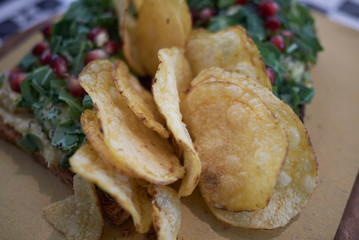 Vegetarian toast with rocket, hummus and pomegranate and chips on the side