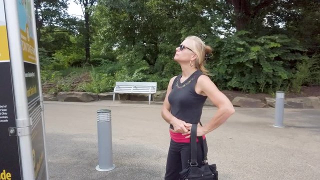 Mature woman looks at map kiosk at Point State Park in Pittsburgh, Pennsylvania.