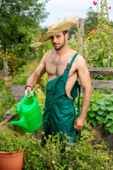 shirtless gardener with straw hat watering flowers