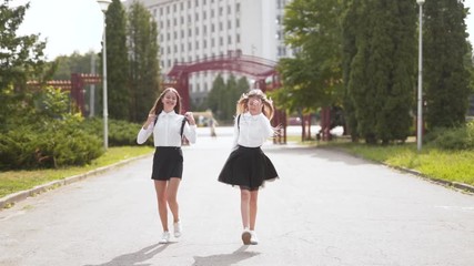 Happy go lucky schoolgirl walk and dance on path together holding hands - Powered by Adobe