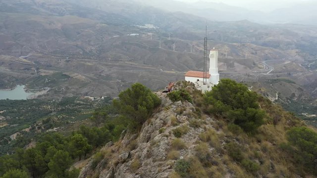 People on a rocky hill with tiny white church in Lecrin Valley, Granada, Spain