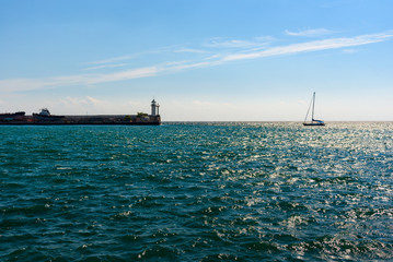 Lighthouse in the port of the resort city of Yalta, on a bright sunny day with clouds in the sky...