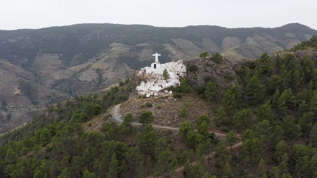 Small white church on mountain top with tourists looking tiny, Andalusia, Spain.