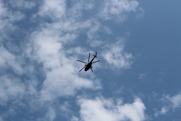 large military helicopter hovers in sky. A camouflaged helicopter flies at high speed.