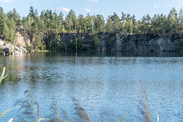 Scenic view from the top of the quarry to the blue water and the opposite rocky shore on a summer sunny day. 
