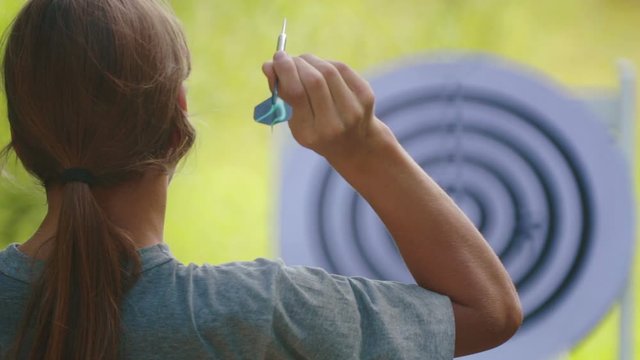 Portrait of a teenager boy playing darts. A boy plays an outdoor darts game.