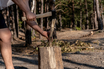 A man chopping wood on a stump in the forest on a sunny summer day. Travel and camping