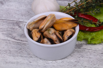 Pickled mussels in the bowl served pepper, garlic and salad