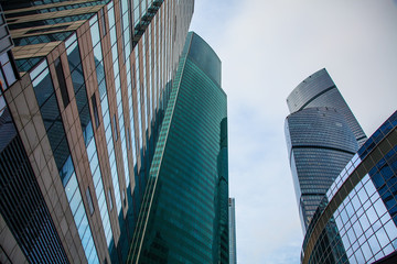 Naklejka premium View of the top of modern glass skyscrapers against the blue sky.