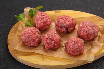 Raw meatball over wooden background