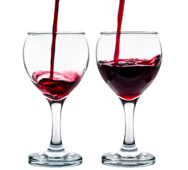 Pouring red wine into the glass against white background