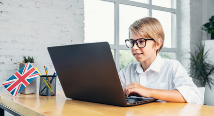Concentrated boy in glasses enjoys learning english online