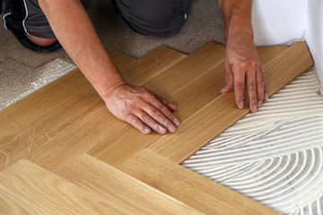 Worker laying parquet flooring. Worker installing wooden laminate flooring