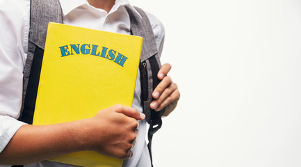 Schoolboy with a schoolbag carrying an English book closeup