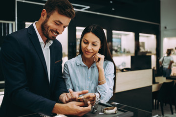 Beautiful couple enjoying in shopping at modern jewelry store.