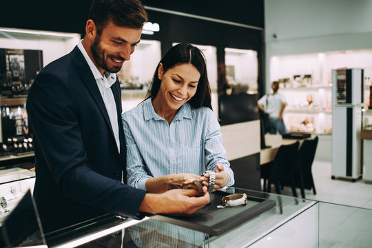 Beautiful couple enjoying in shopping at modern jewelry store.