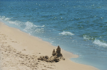 Sand castle on the beach. Sea with waves