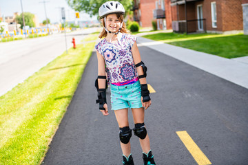 Child on inline skates. Little girl skating on sunny summer day.