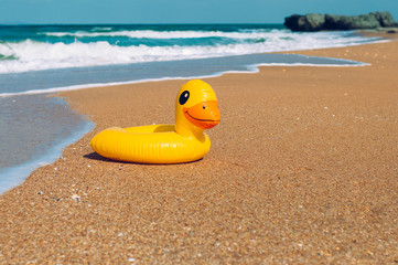 Fototapeta na wymiar Inflatable rubber duck swimming ring on the sand near sea on the beach