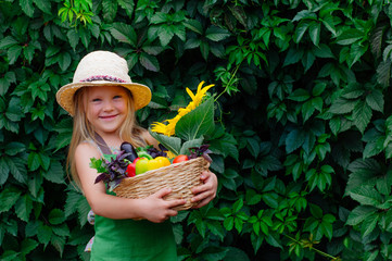 Smiling little girl holding basket with fresh vegetables