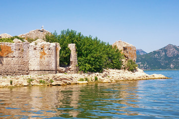Picturesque lake with a ruined fort on a small island. View of Lake Skadar on sunny summer day. Fortress Grmozur. Montenegro