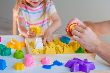 Father and little girl playing with colorful kinetic sand