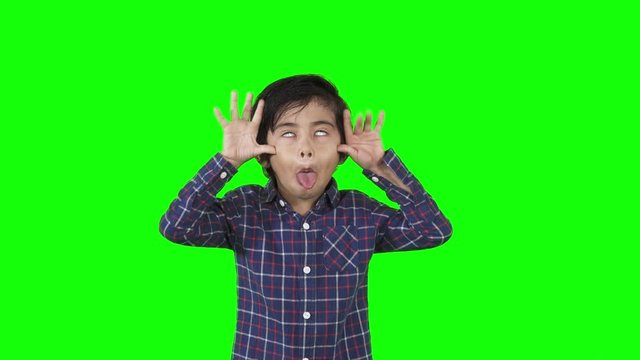 Little boy showing a mocking or silly gesture in the studio. Shot in 4k resolution with green screen background