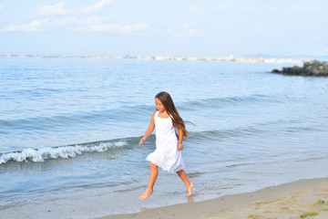 Fototapeta na wymiar barefoot girl runs on the sand on the beach.Summer marine weekend