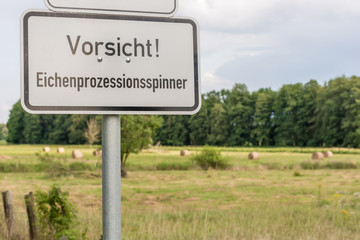 Warnung vor dem Eichenprozessionsspinner auf einem Schild mit der Aufschrift in deutscher Sprache Vorsicht Eichenprozessionsspinner