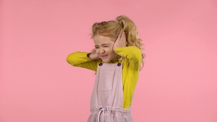 Little cute girl is covering her ears in studio