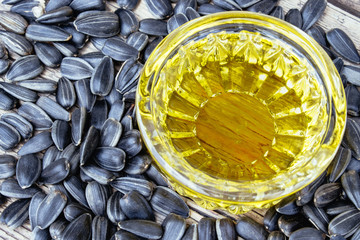 Sunflower oil and sunflower seeds on a wooden background. Healthy foods and fats.