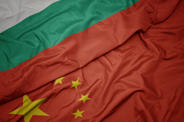 waving colorful flag of china and national flag of bulgaria.
