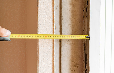 A worker measures the window opening with a tape measure