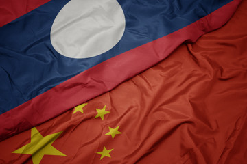 waving colorful flag of china and national flag of laos.