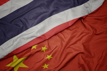 waving colorful flag of china and national flag of thailand.