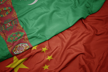waving colorful flag of china and national flag of turkmenistan.