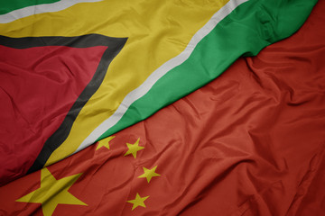 waving colorful flag of china and national flag of guyana.