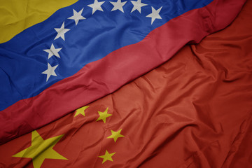waving colorful flag of china and national flag of venezuela.