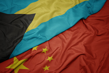 waving colorful flag of china and national flag of bahamas.