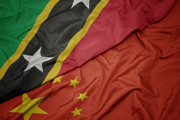 waving colorful flag of china and national flag of saint kitts and nevis.