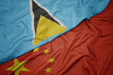 waving colorful flag of china and national flag of saint lucia.