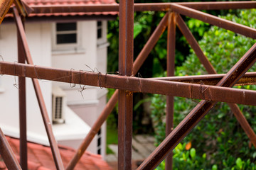 Rust on the steel frame of old advertising billboard with blurry house roof.
