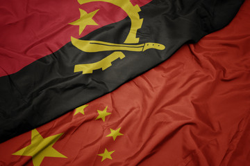 waving colorful flag of china and national flag of angola.
