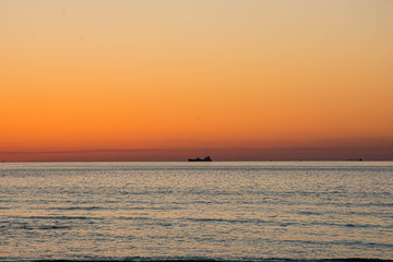 Beautiful orange sky sunset view with ship silhouette in uae beach