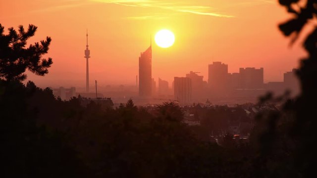 Time-lapse of sunrise over Donaucity in Vienna seen from the outskirts. Sunshine dives famous skyscrapers in dazzling bright light, showing merely the silhouettes of the skyline.