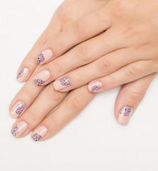 Beautiful flowers on a white lacquer on the nails on a multicolored background.
