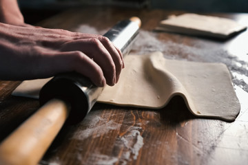 rolling out the dough with rolling pin on the table.